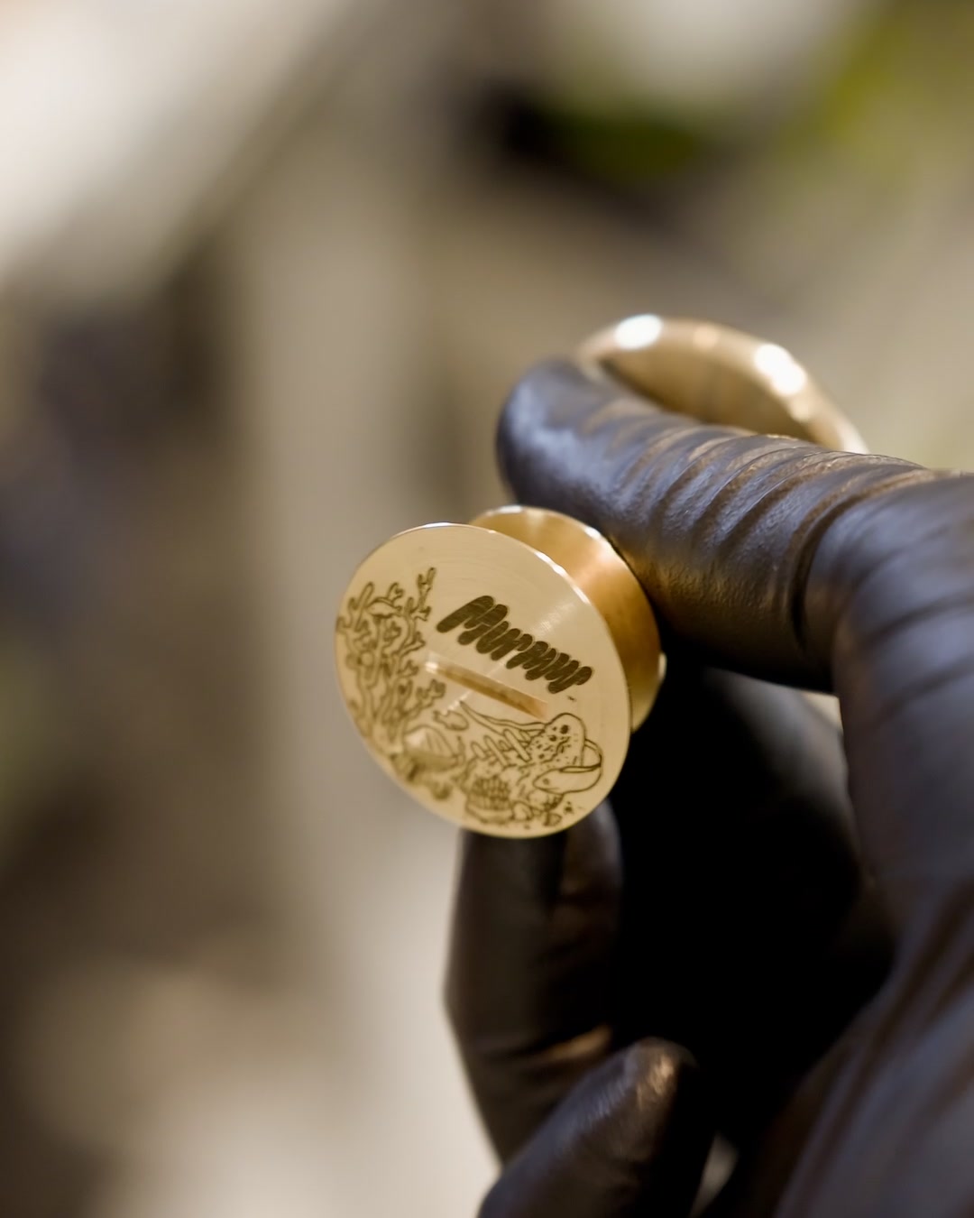 The engraved solid brass cigar rest of The Object: Cigar, held in a gloved hand